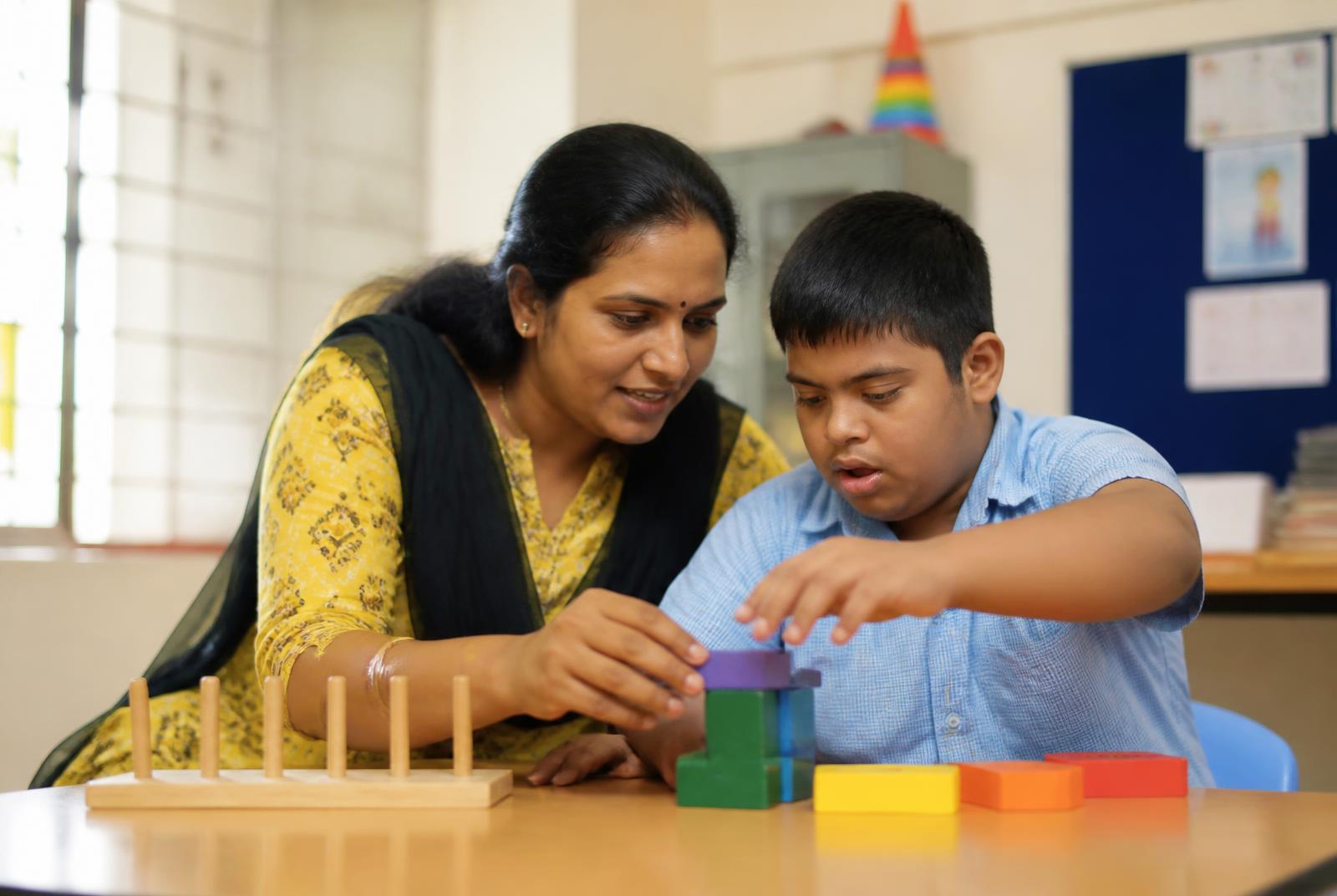 A teacher guiding a young student with a disability through a learning activity